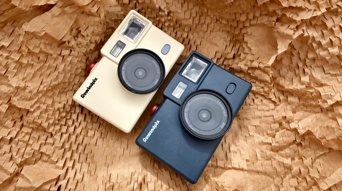 Cream and dark gray Rewindpix cameras on honeycomb packing paper
