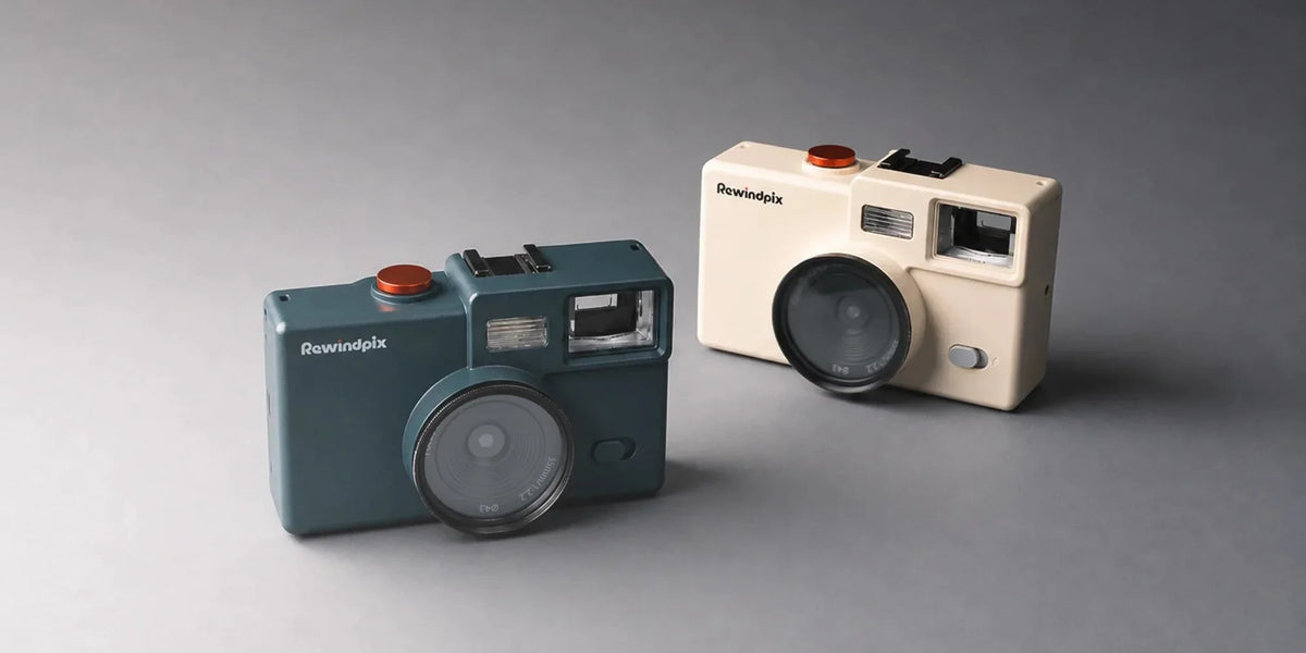 Dark teal and cream Rewindpix cameras on a gray surface